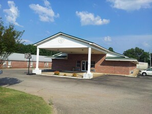 A single-story brick building with a white roof and a covered porch.