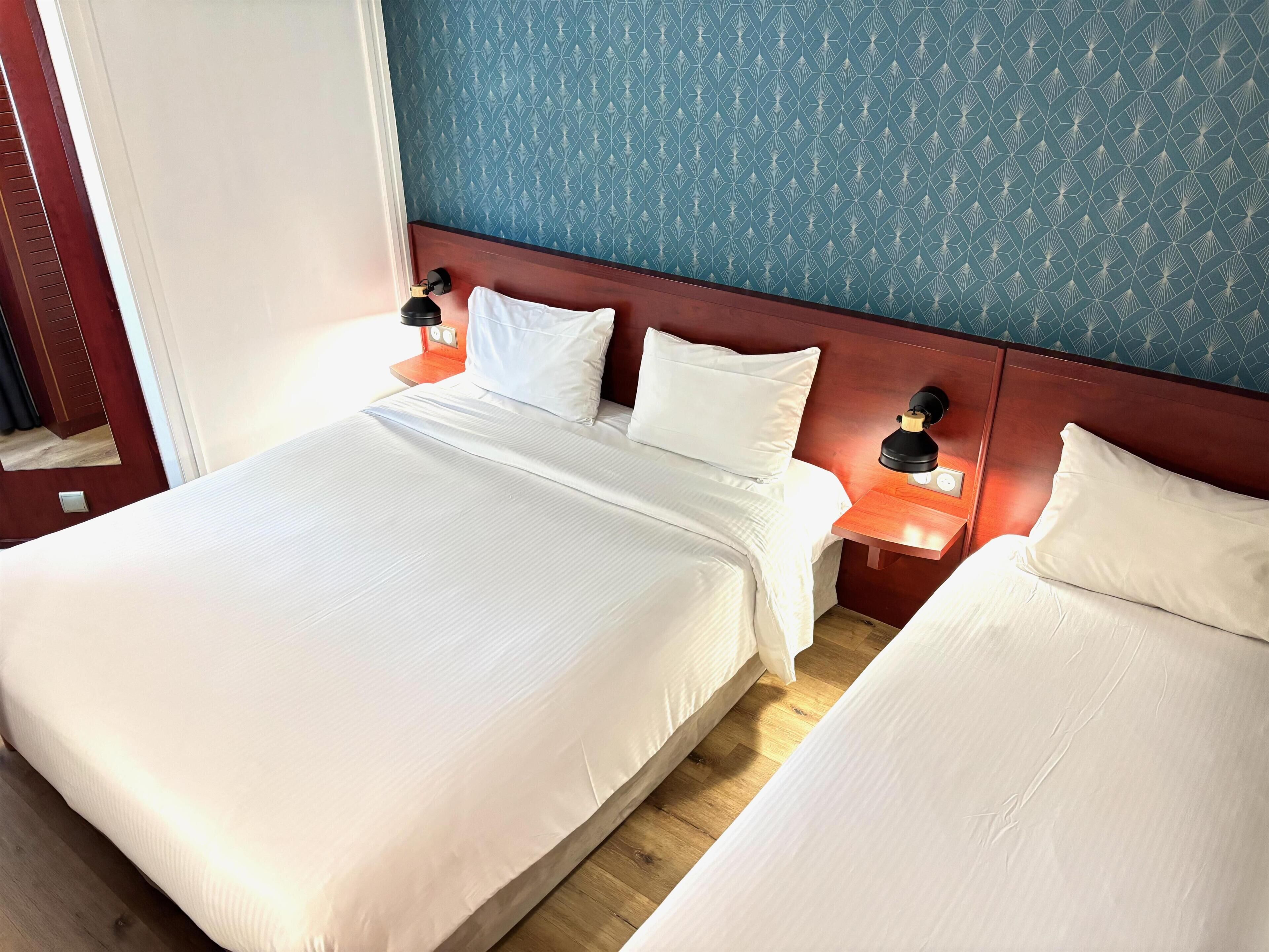 Habitación de hotel con una cama grande, dos mesitas de noche con lámparas y un papel tapiz estampado.