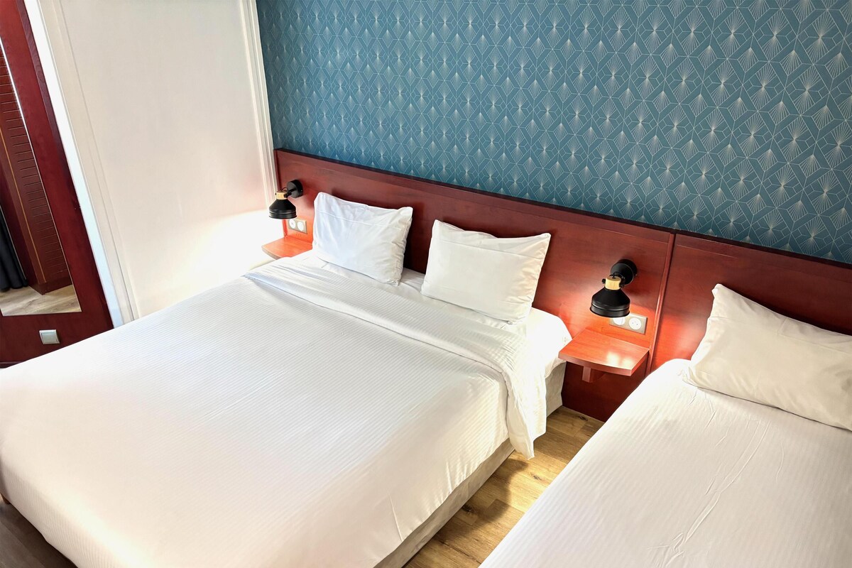 A hotel room with a large bed, two bedside tables with lamps, and a patterned wall.
