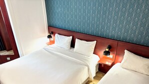 Une chambre d’hôtel avec un grand lit, deux tables de chevet et une tête de lit.