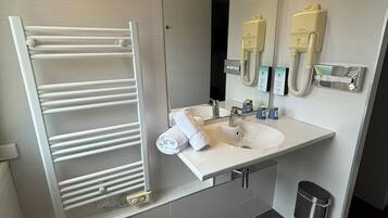 Une salle de bain moderne avec un lavabo blanc, un miroir, un porte-serviettes et une douchette à main.