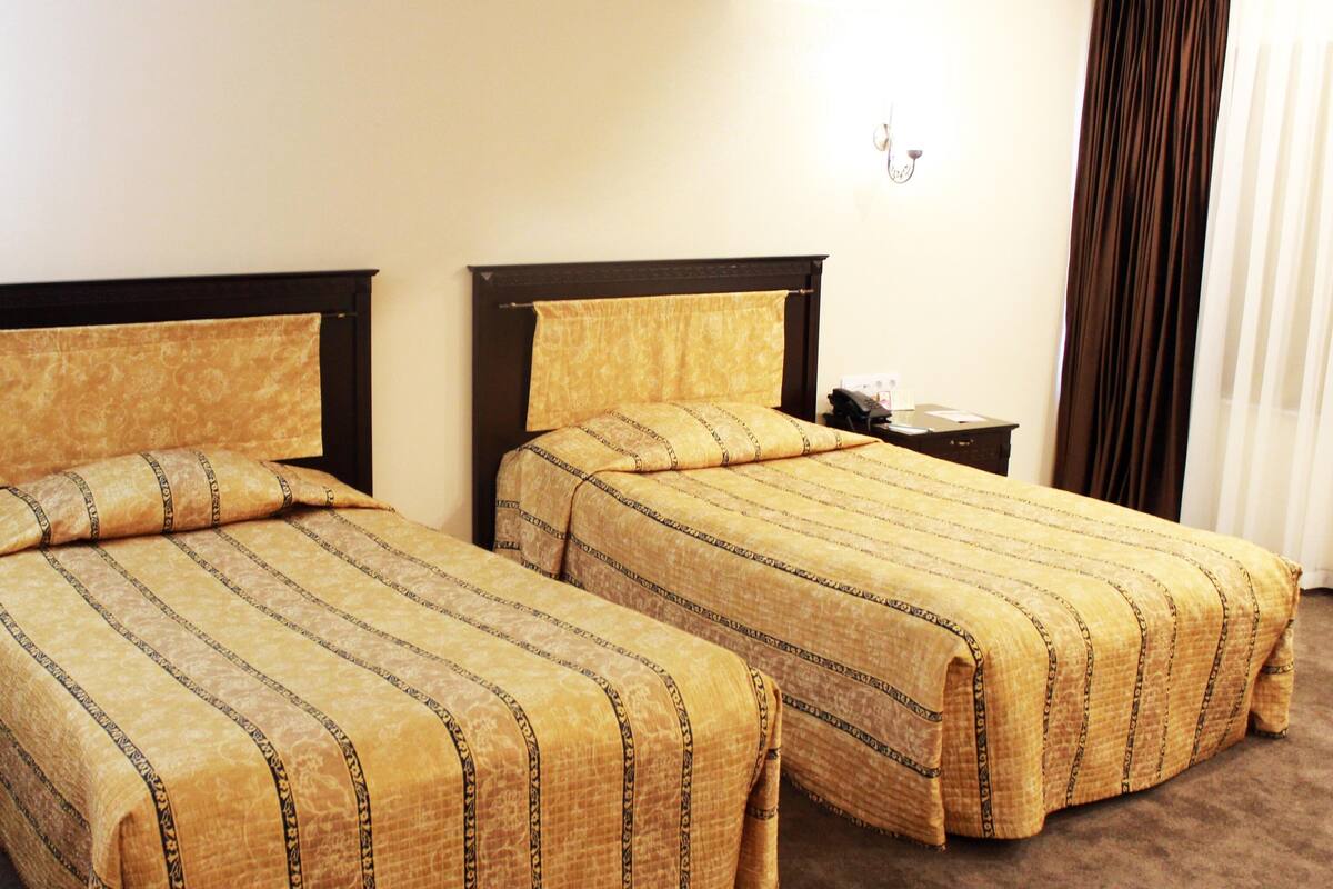 Two single beds with matching headboards and footboards, a bedside table, and a nightstand with a lamp.