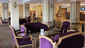 A lobby with purple upholstered seating, a glass coffee table, and a reception desk. - Grand Mir Hotel (Tashkent)