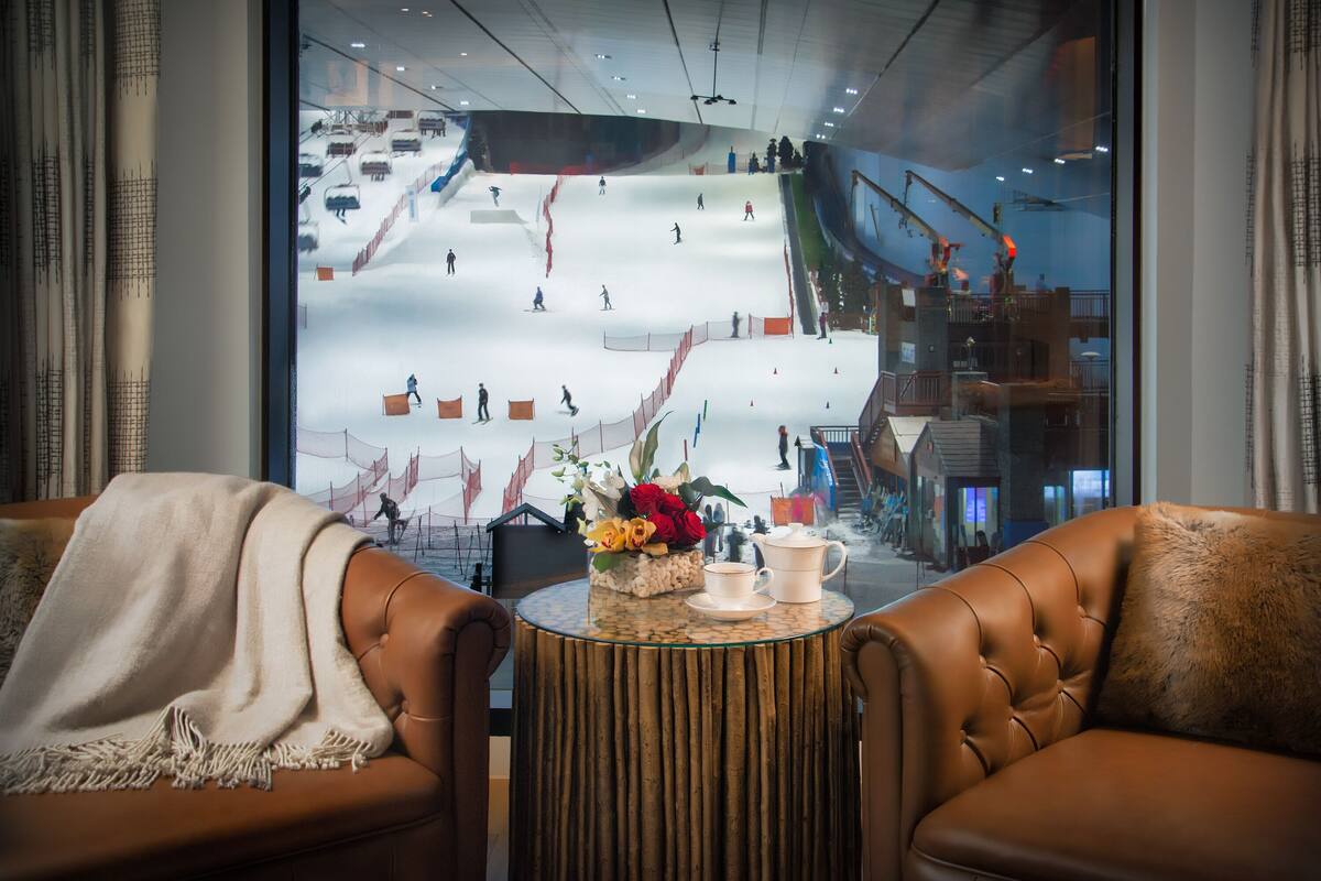 Un coin salon confortable avec vue sur une piste de ski, grâce à une grande fenêtre.