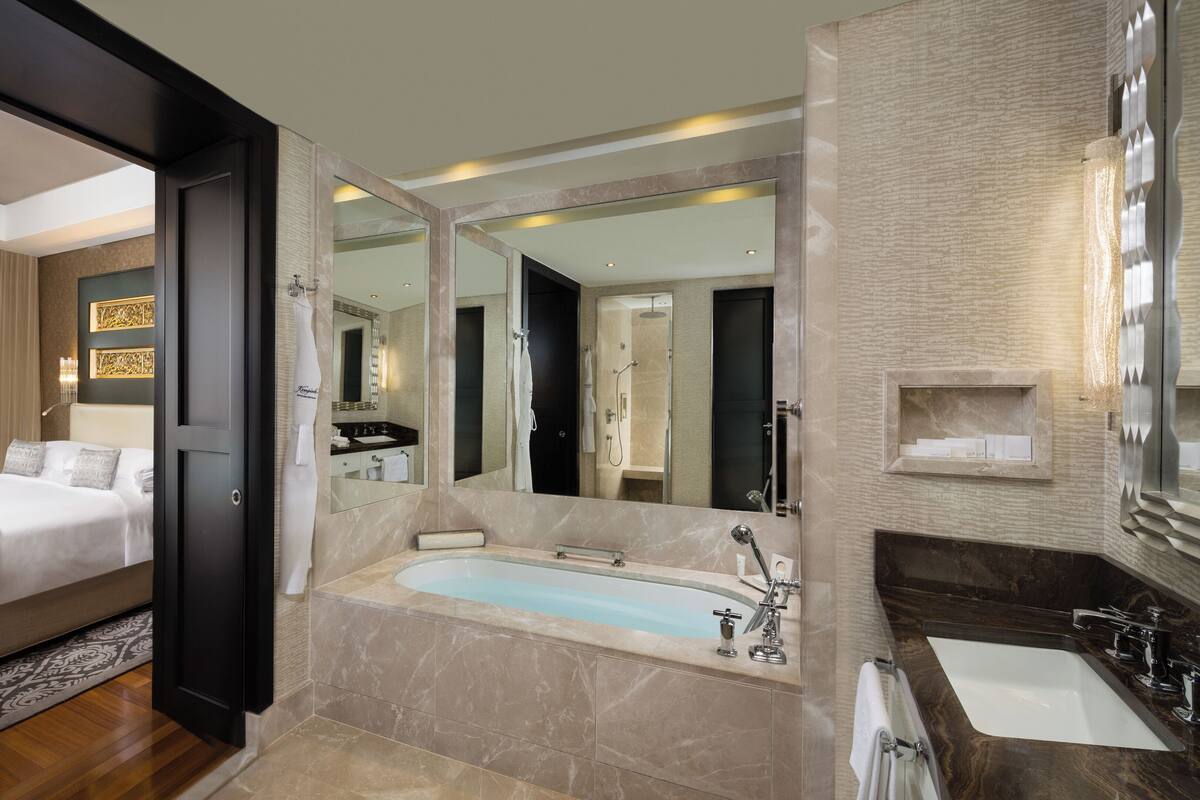 Une chambre d’hôtel moderne dotée d’un grand lit, d’une baignoire, d’une coiffeuse avec miroir et offrant une vue sur la ville.