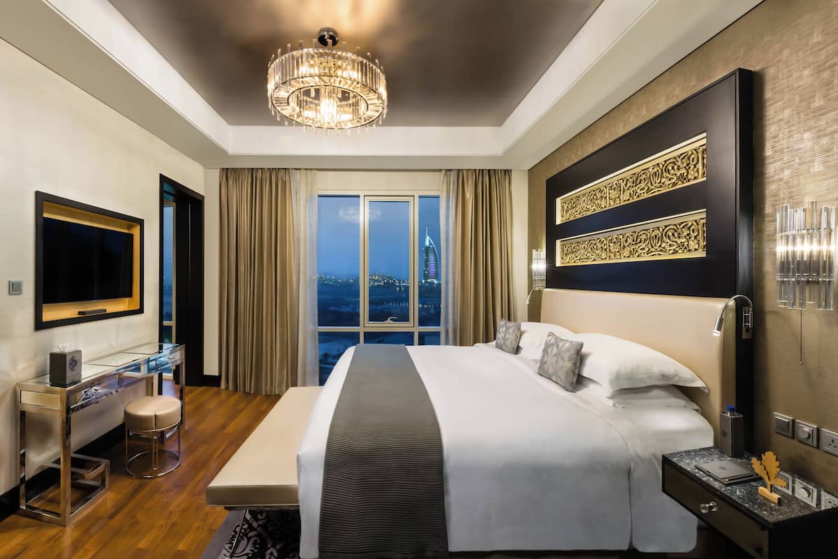 Une chambre d’hôtel moderne, dotée d’un grand lit, d’un bureau, d’une télévision et offrant une vue sur le paysage urbain.