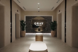 A hallway leading to a wellness club named 'GRAY' with a marble wall, potted plants, and a central seating area. - Kempinski Mall Of The Emirates (Dubai)
