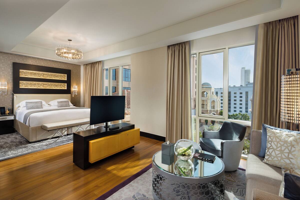 Une chambre d’hôtel moderne dotée d’un grand lit, d’une télévision, d’un canapé et d’un balcon offrant une vue sur la ville.