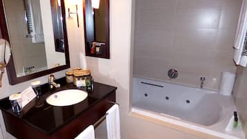 Un baño moderno con tocador de madera oscura, un espejo grande, un lavabo y una bañera.