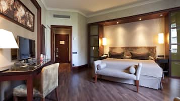 Ein Hotelzimmer mit Bett, Nachttischen, einem Schreibtisch mit Stuhl, einem Fernseher und Bildern an der Wand.