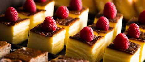 Diversos postres cuadrados con una capa superior dorada, algunos coronados con frambuesas.
