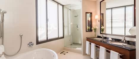 Un baño moderno con una bañera grande, una ducha con mampara de vidrio y un tocador con espejo.
