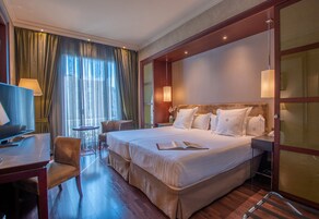 Une chambre d’hôtel avec un grand lit, un bureau, une chaise et un téléviseur.