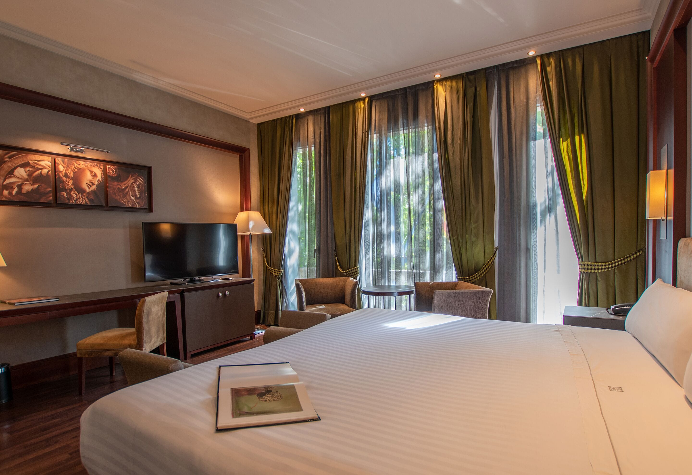 Una habitación de hotel con una cama grande, un escritorio con televisor, una silla y una mesita.