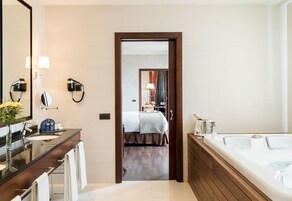 A modern bathroom with a large mirror, two wall-mounted hair dryers, a sink, and a bathtub.