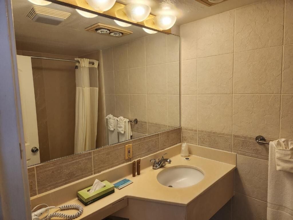 Een badkamer met een wastafel, spiegel en handdoekhouder.