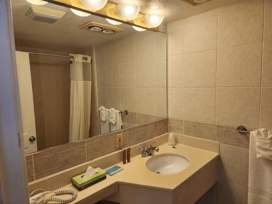 Een badkamer met een wastafel, spiegel en handdoekhouder.