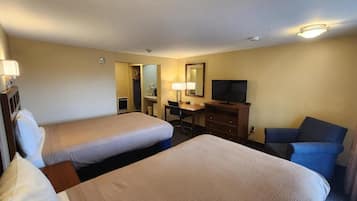 A hotel room with two beds, a desk, a chair, a television, and a mirror.