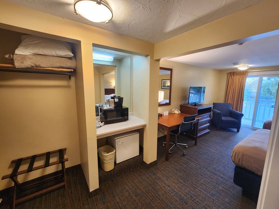 Habitación de hotel con literas, un escritorio con computadora, una silla, un televisor y vistas al exterior.