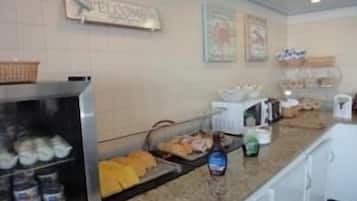 A buffet area with a welcome sign, various food items, and condiments.