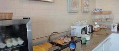 A buffet area with a welcome sign, various food items, and condiments.
