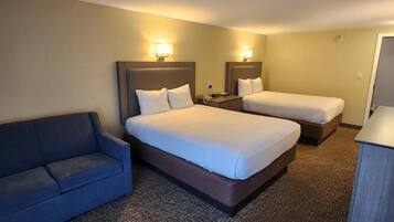 Habitación de hotel con dos camas, un sofá y un escritorio.