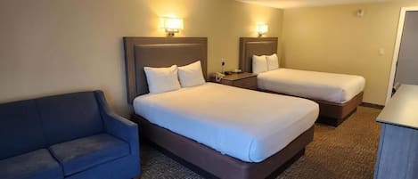 Une chambre d’hôtel avec deux lits, un canapé et un bureau.
