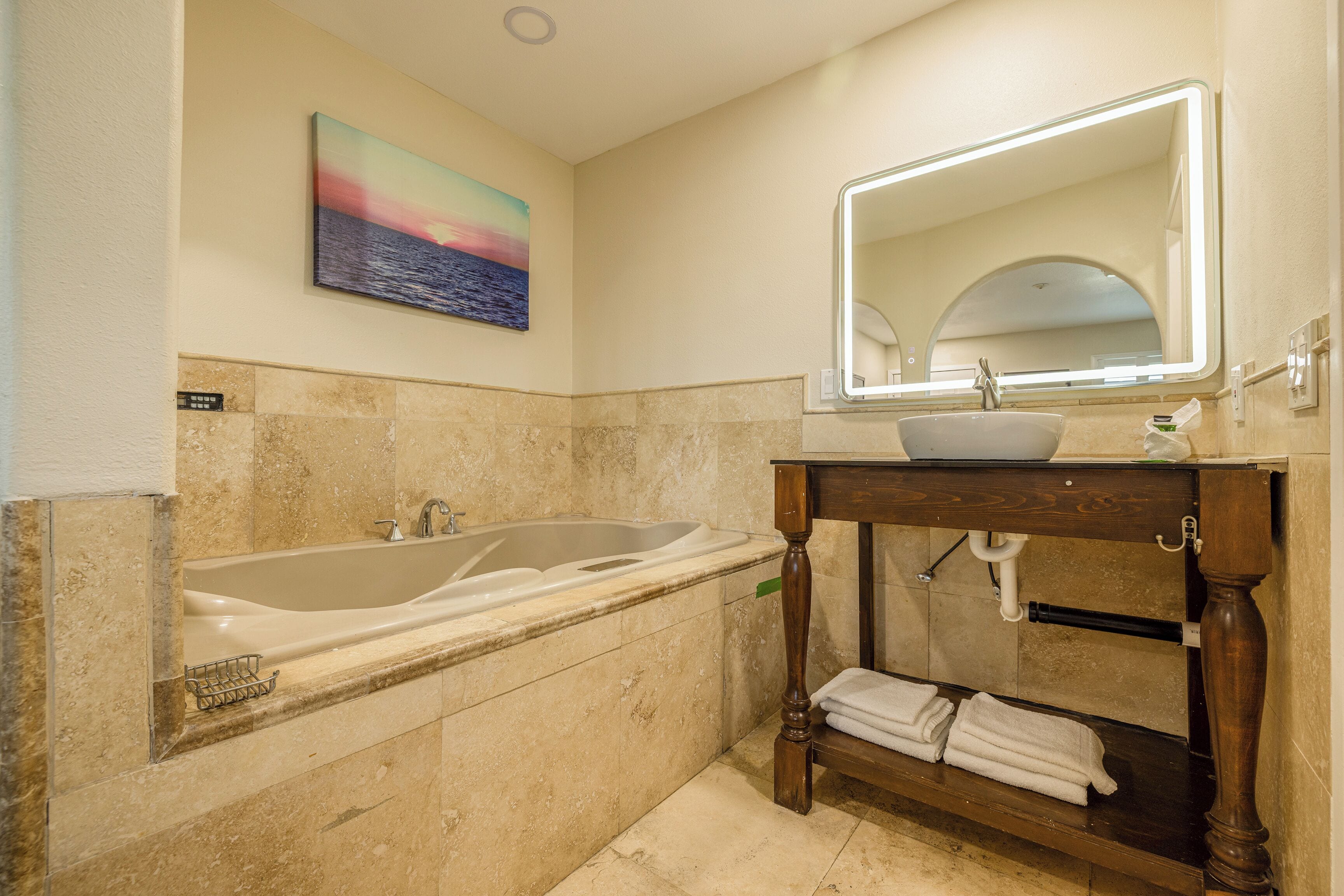 A bathroom with a bathtub, a sink, a mirror, and a towel rack.