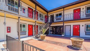 A multi-story building with balconies, red doors, and a central staircase. - Hotel Avenida Victorville I 15 (Victorville)
