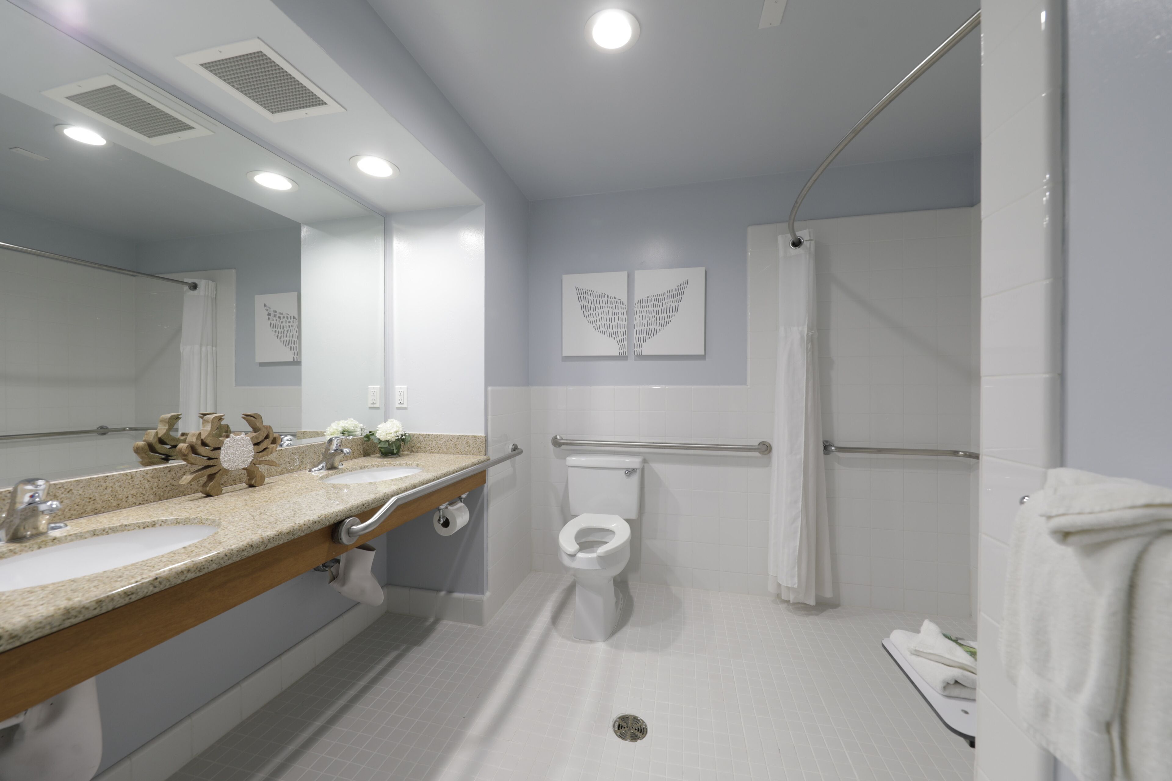 A modern bathroom with two sinks, a toilet, and a shower area.