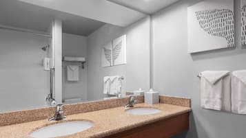 A modern bathroom with two sinks, a large mirror, and artwork on the walls.