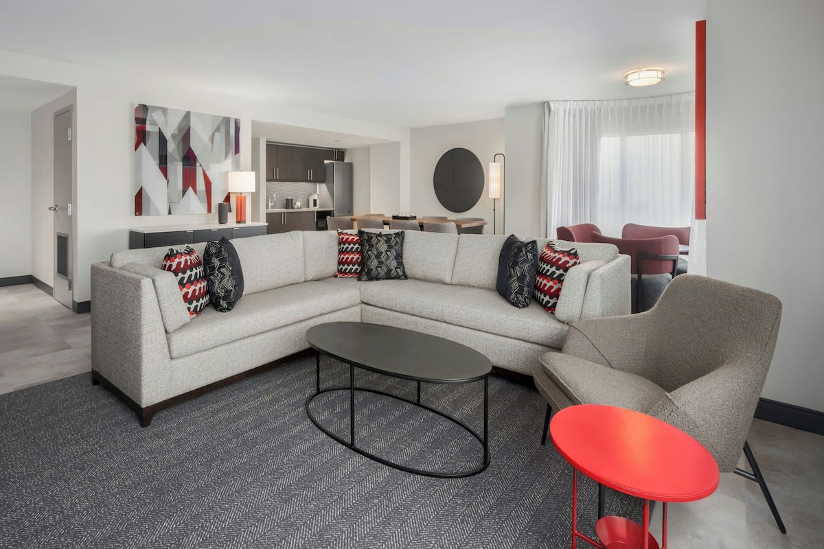 A modern living room with a sectional sofa, a coffee table, and a red accent chair.