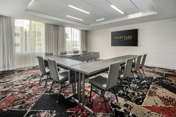 A conference room with a long table, grey chairs, and a black and red patterned carpet. - Courtyard by Marriott Athens Downtown (Athens)