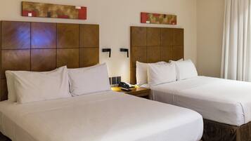 A hotel room with two beds, a nightstand with a phone, and artwork on the walls.