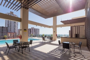 Una piscina al aire libre, sombrillas, sillones reclinables de piscina