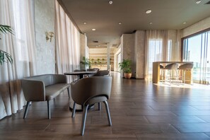 A spacious hotel lobby with a modern design, featuring a seating area with sofas and chairs, a reception desk, and large windows allowing natural light. - Crowne Plaza Asuncion by IHG (Asunción)