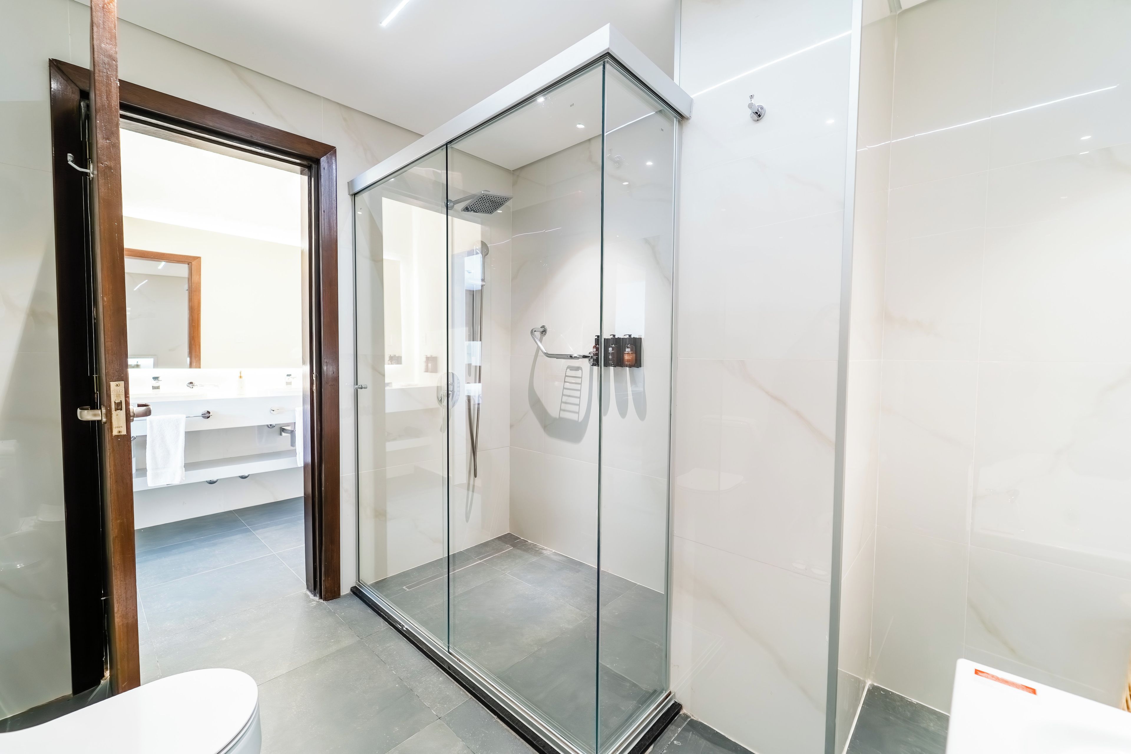 Un baño moderno con cabina de ducha de vidrio, inodoro y zona de lavamanos.