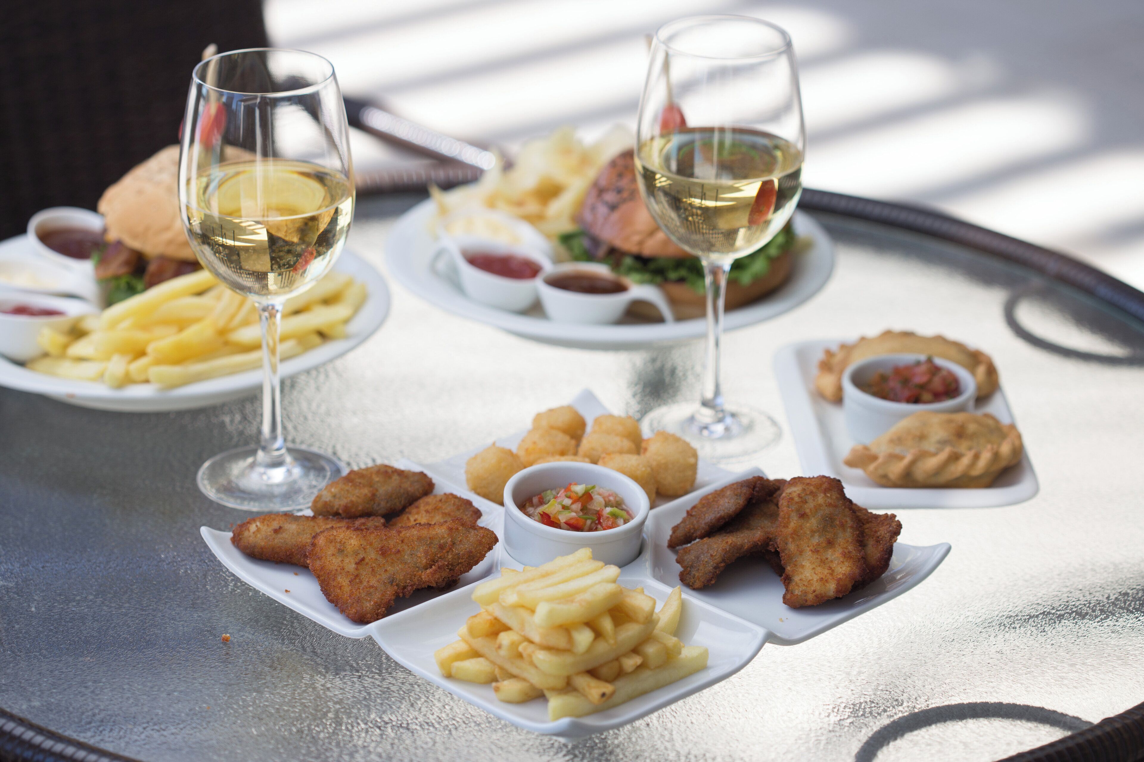 Uma mesa com diversos alimentos e dois copos de vinho branco.