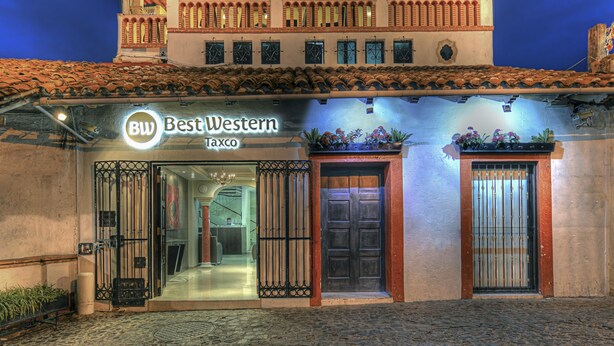 A two-story building with a balcony, a sign reading "Best Western Taxco," and a cobblestone entrance. - Best Western Taxco (Taxco)