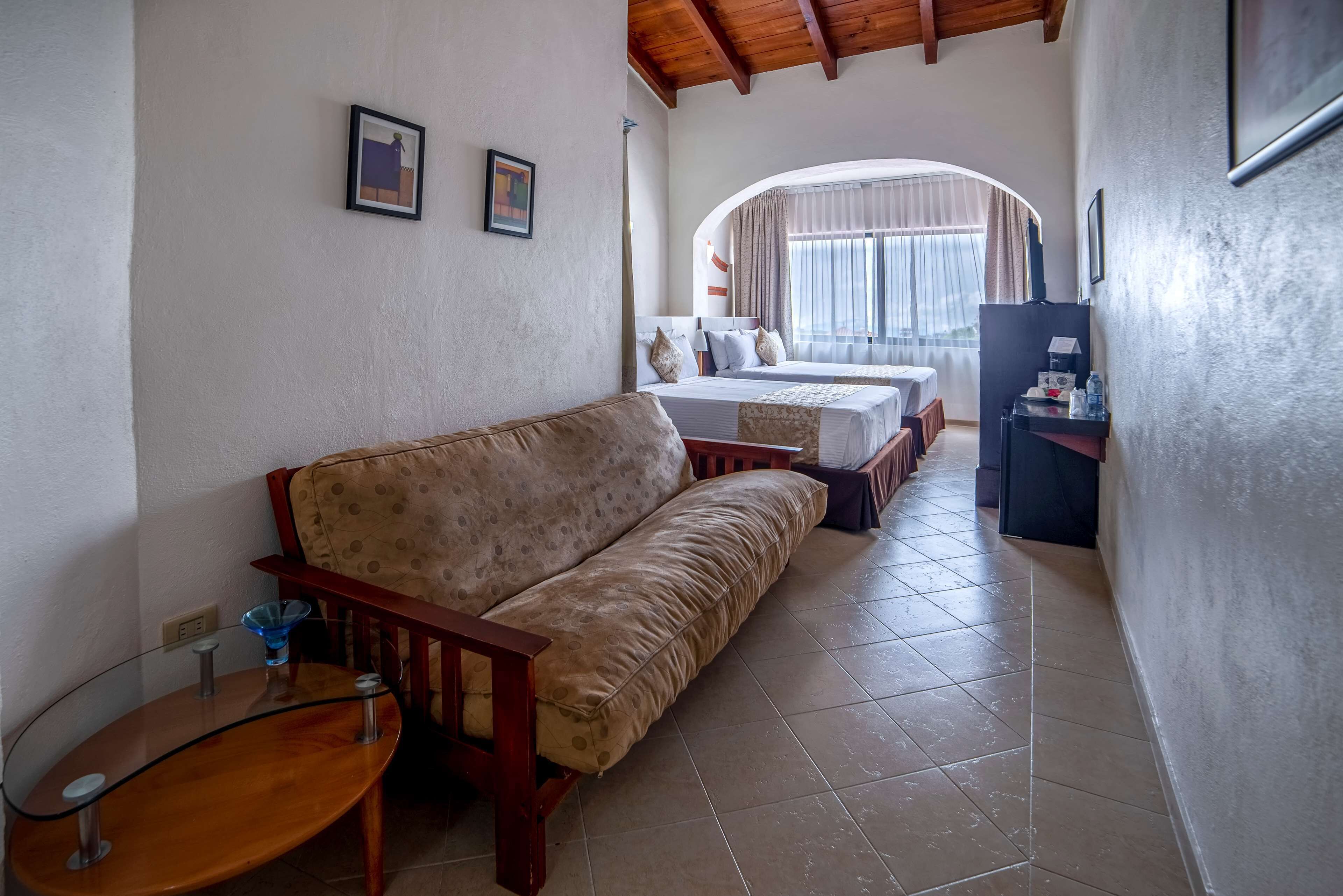 A cozy hotel room with a sofa, a small table, and a bed with a view of the outdoors.
