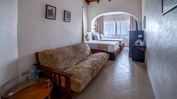 A cozy hotel room with a sofa, a small table, and a bed with a view of the outdoors.