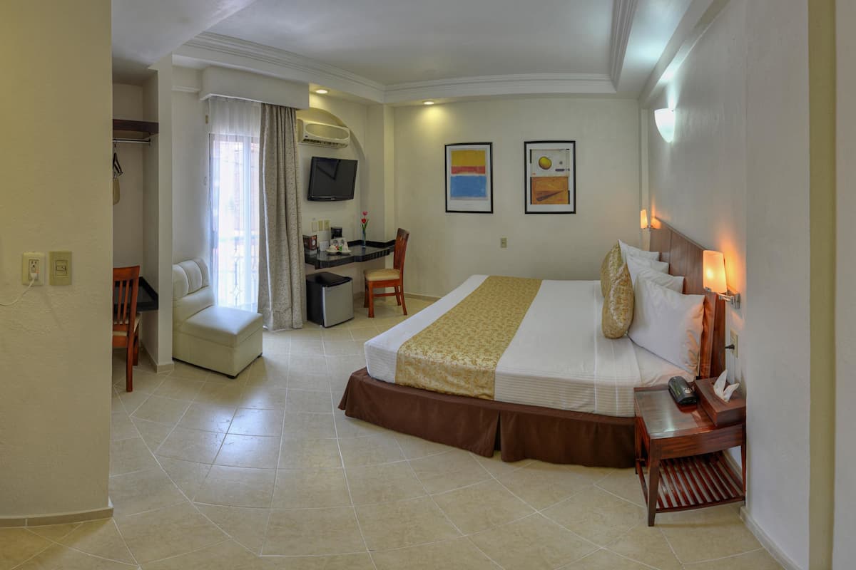 A hotel room with a bed, desk, chair, and a television.