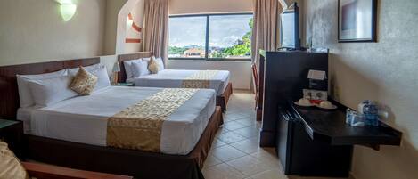 Habitación de hotel con dos camas, un escritorio, una silla, un televisor y una ventana con vistas.