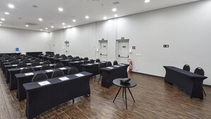 Ett konferensrum med rader av bord och stolar, en brandsläckare och en nödutgångsdörr.