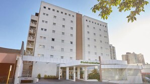 Ett modernt hotell med en vit fasad, flera våningar och en central entré med ett glastak.