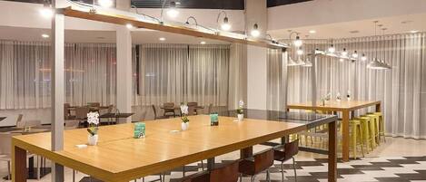 Una sala de conferencias moderna con una larga mesa de madera, varias sillas e iluminación colgante.