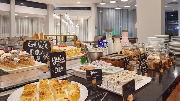 En buffé med olika sorters mat och etiketter, inklusive "Gula Doa" och "Geleia".