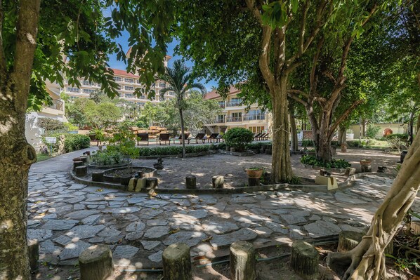 A courtyard with stone paving, trees, and outdoor seating. - Bella Villa Cabana (Pattaya)
