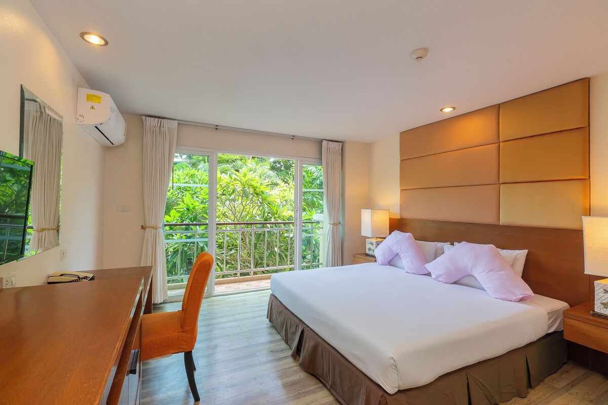 A hotel room with a bed, bedside lamps, a desk, and a chair.
