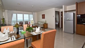 A modern living room with a dining area, a kitchen, and a balcony with a view. - Bella Villa Cabana (Pattaya)